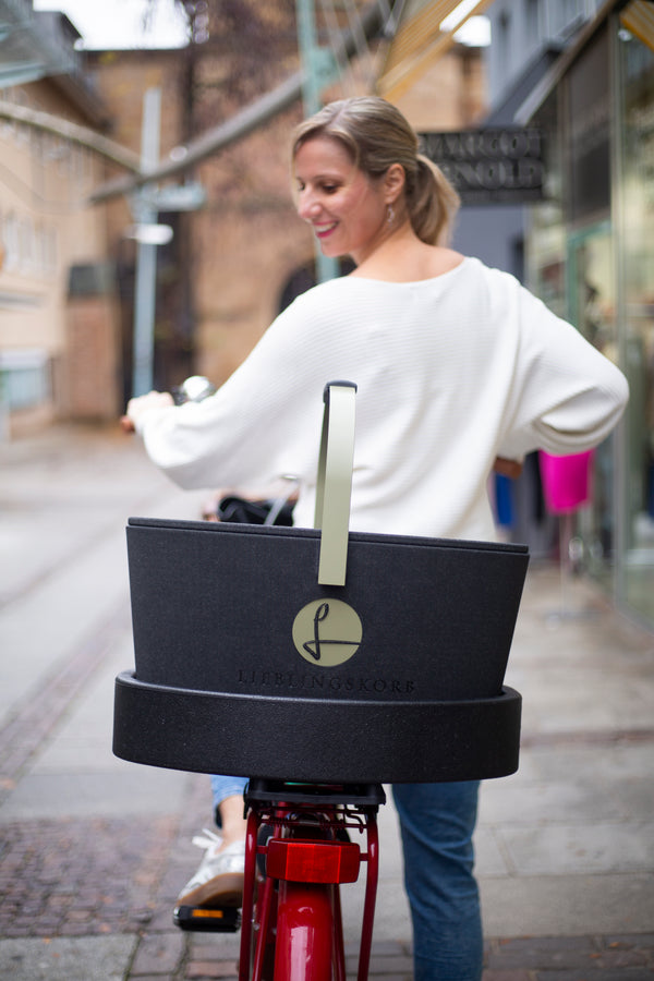 Frau fährt Rad mit LIEBLINGSKORB auf dem Gepäckträger